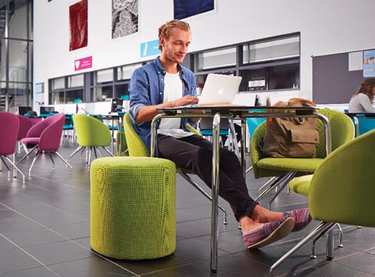 Student at table with green chairs