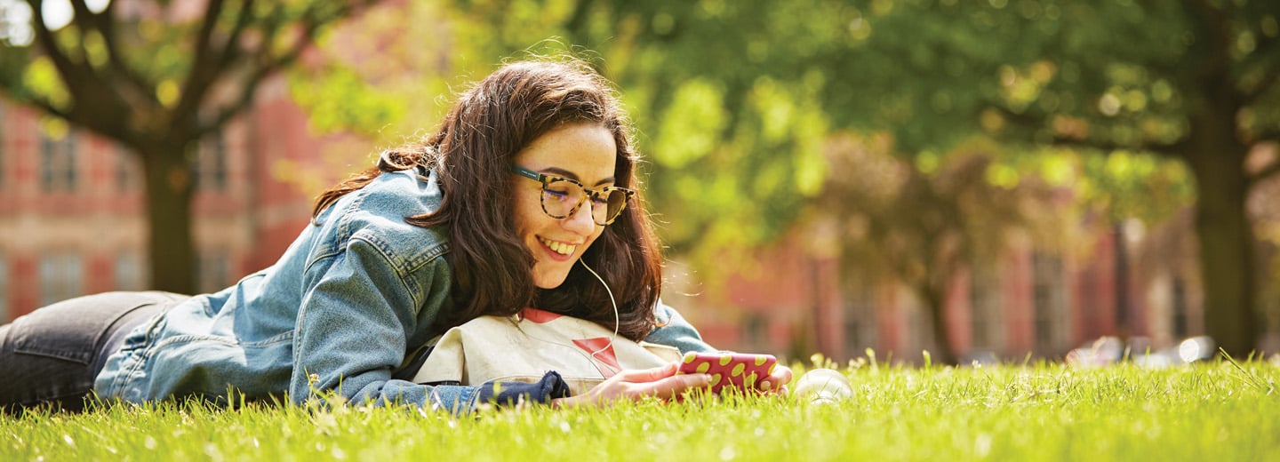 woman laying on grass in front of university