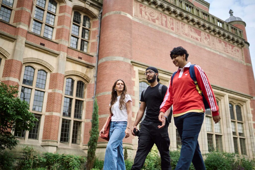 three students walking in front of red brick building